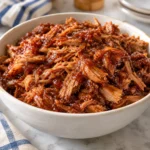 Art's Barbeque, shredded pork in a glossy tomato-based sauce in a serving dish.